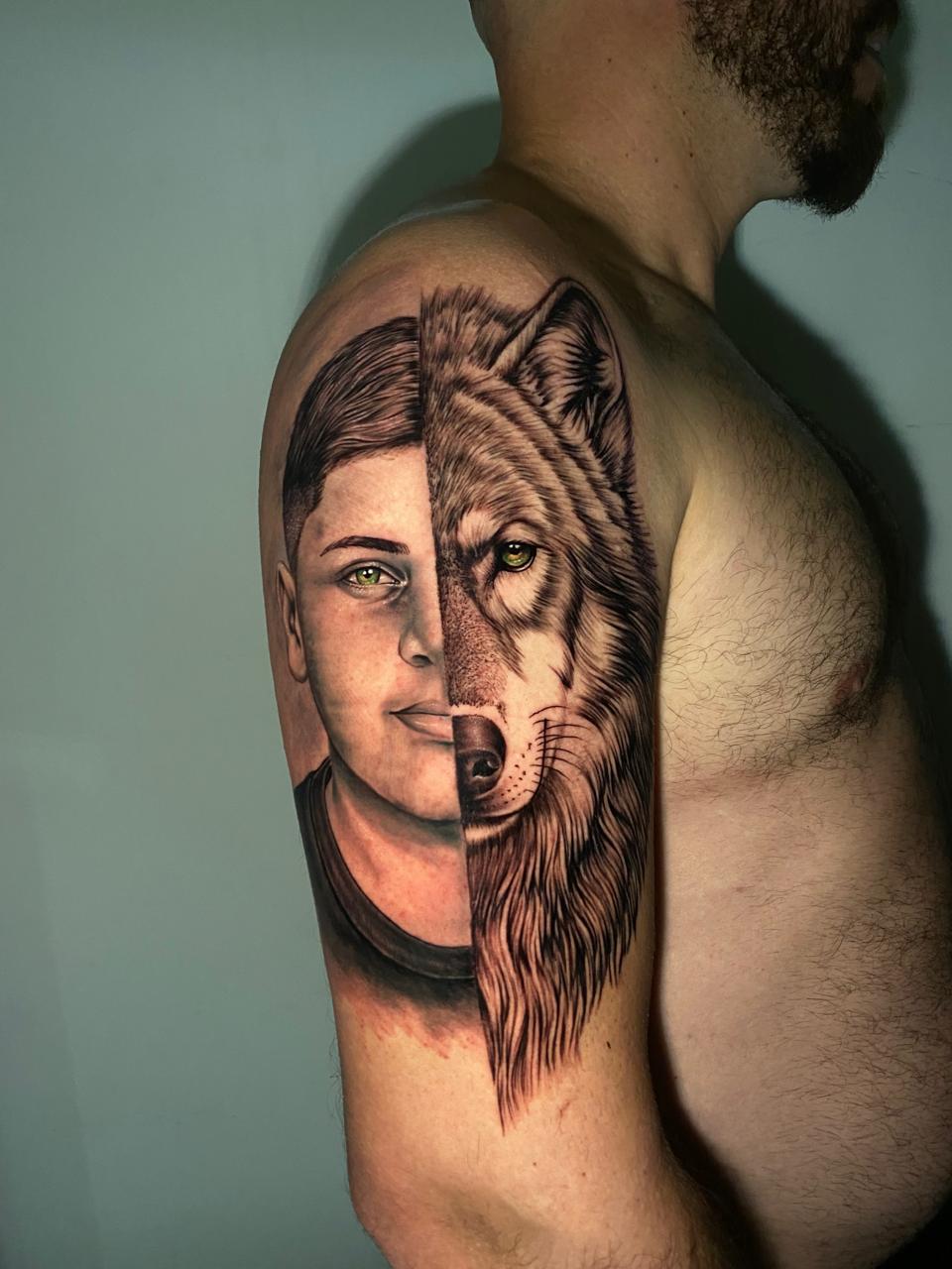 Tatuagem realista de rosto dividido com lobo no braço, preto e cinza
